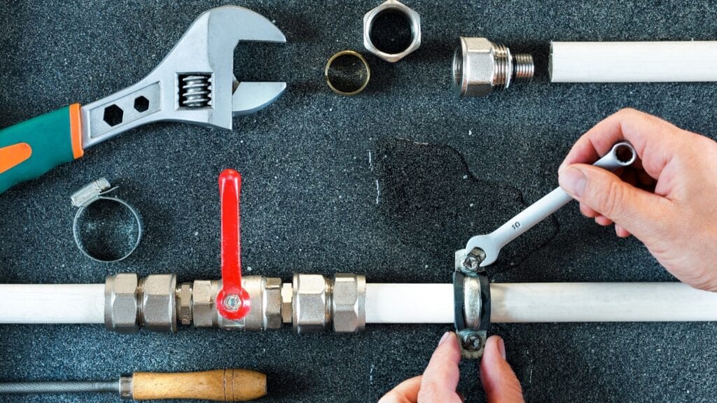 Plumber repairing a pipe valve with an adjustable wrench in Fort Pierce