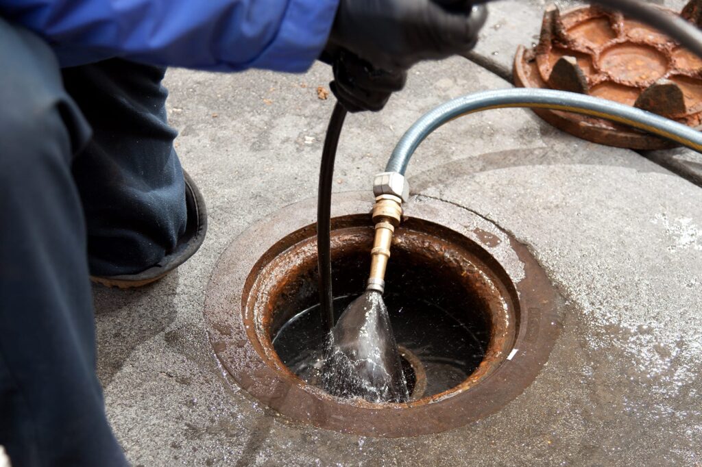 Plumber hydro jetting a sewer line through a manhole in Fort Pierce