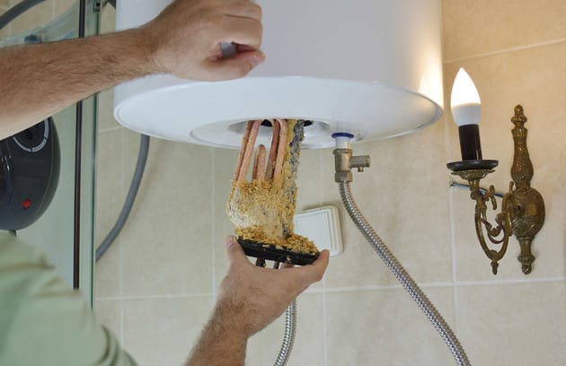 Technician removing mineral buildup from a water heater in Fort Pierce